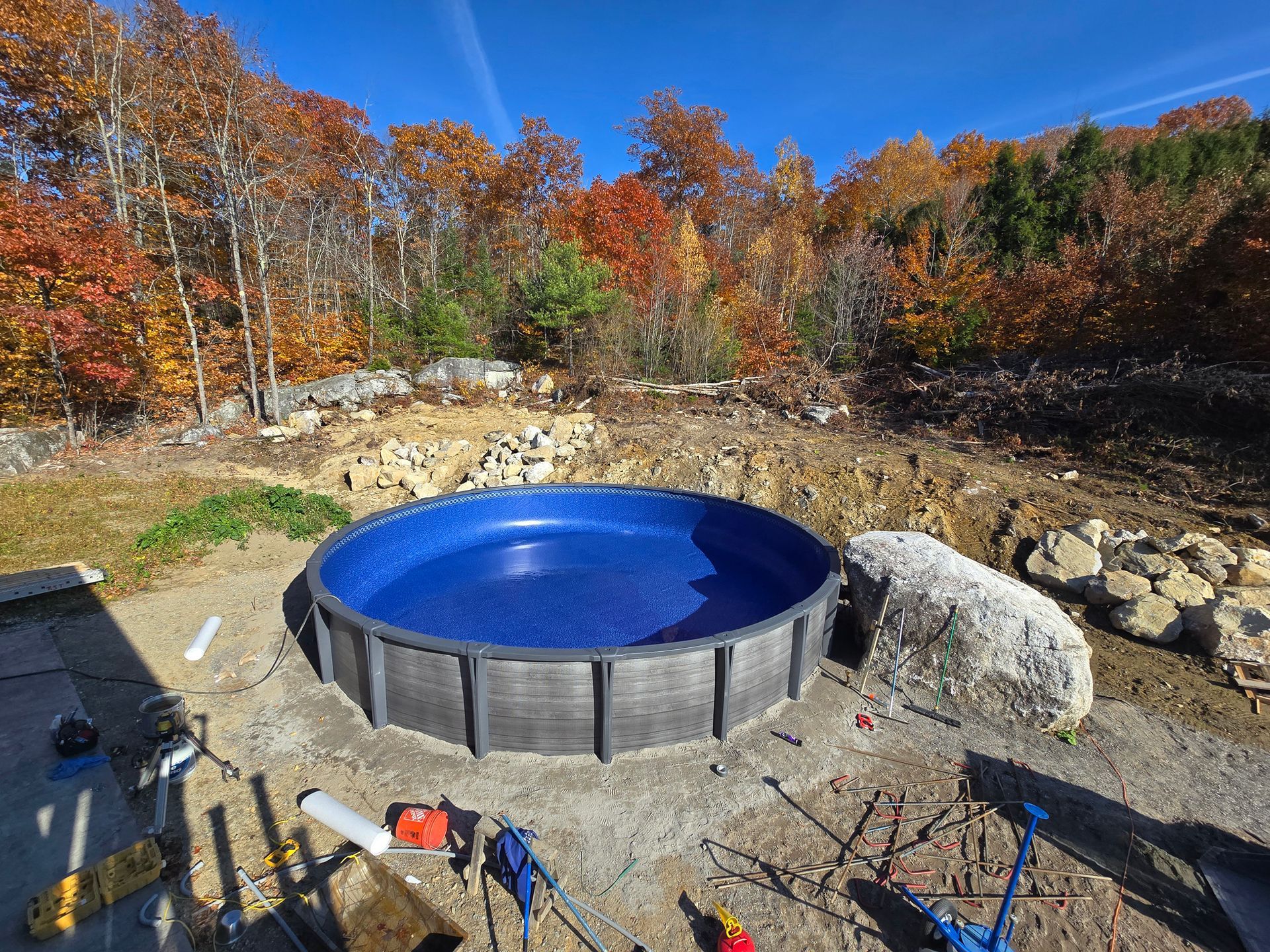 A large blue pool is being built in the middle of a dirt field.
