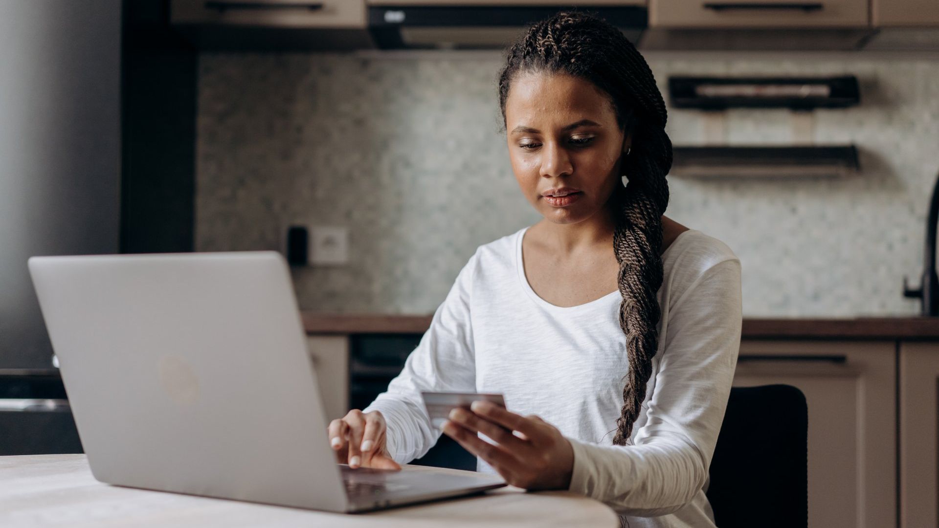 Woman holding her credit card while using a laptop