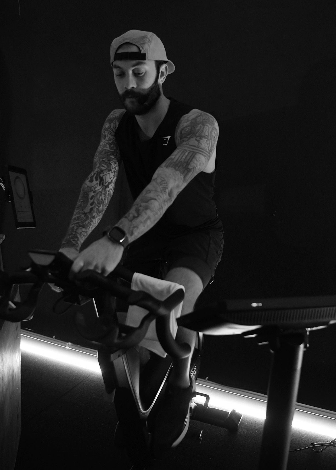 Person riding a stationary bike in a dimly lit gym, with neon floor lighting.