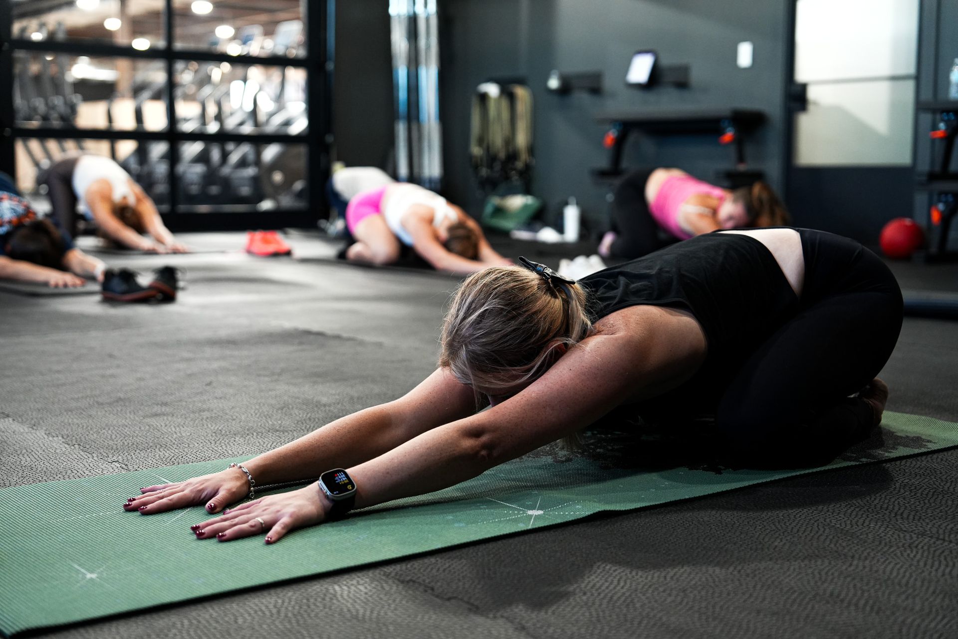 People stretching on yoga mats in a gym during a floor workout class
