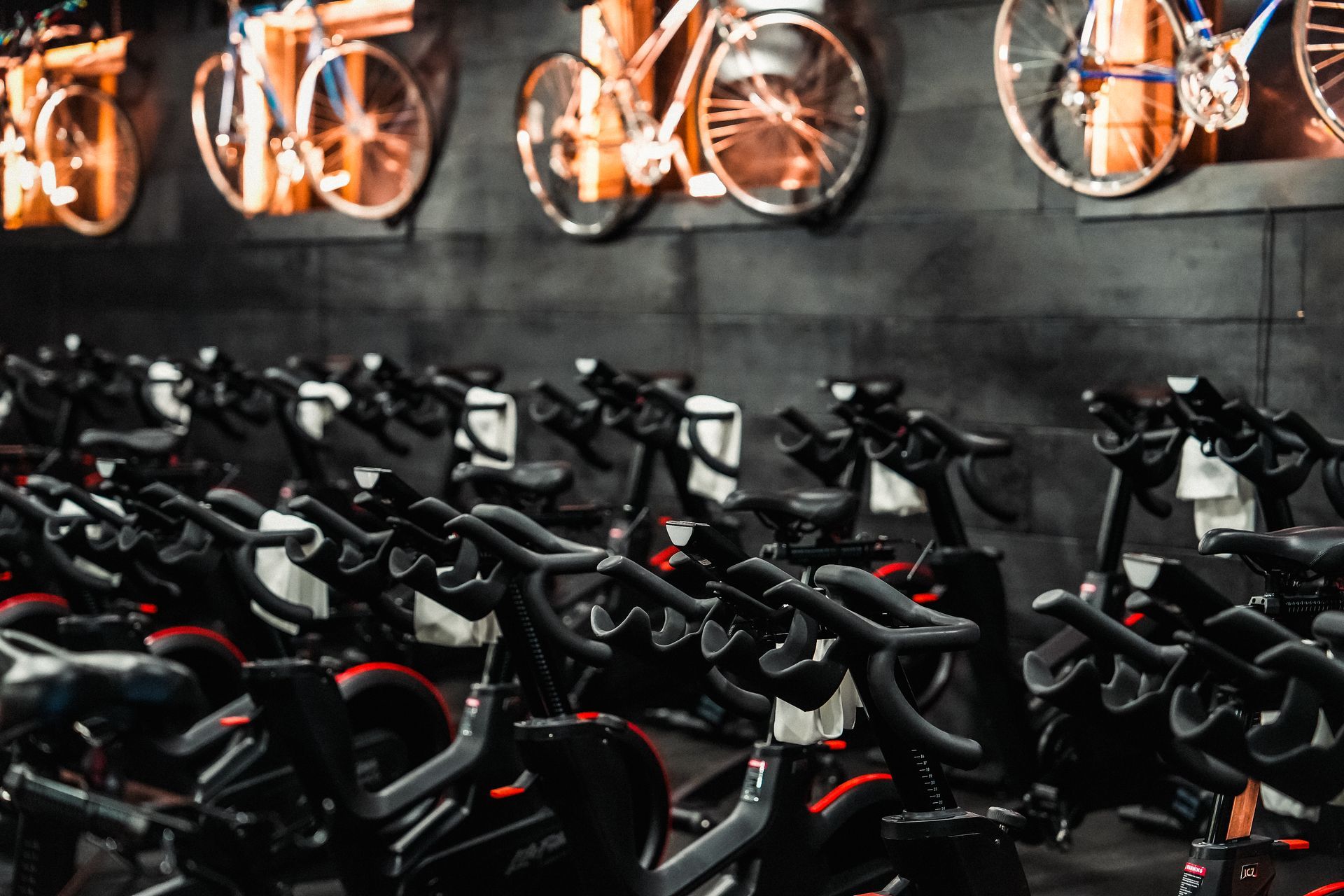 People exercising on stationary bikes in a gym, smiling and chatting during a group workout
