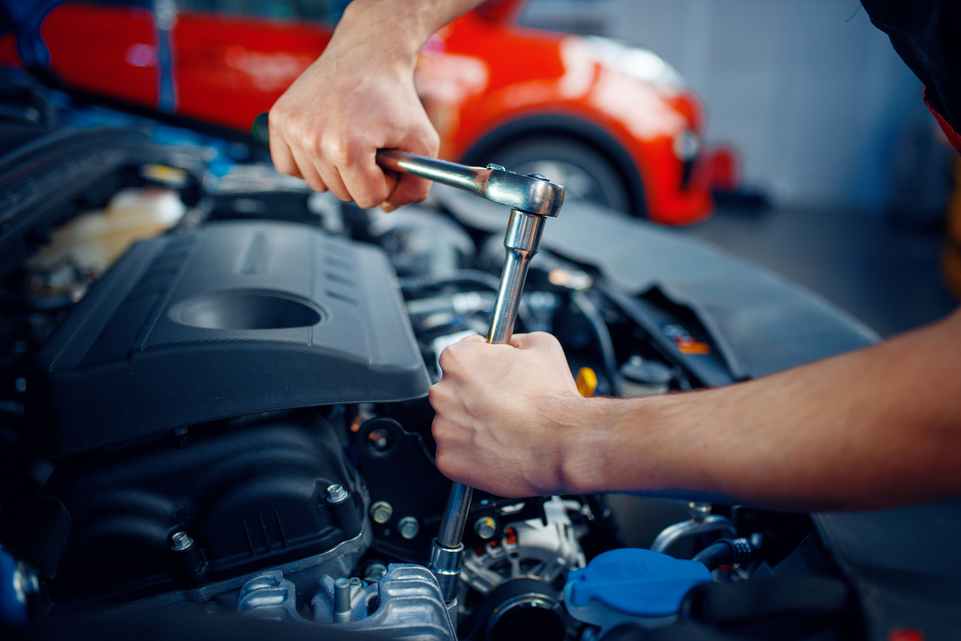 A man is working on the engine of a car with a wrench.
