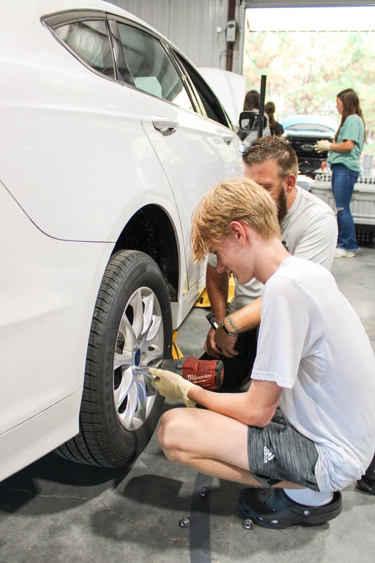 A group of people are working on a car in a garage.