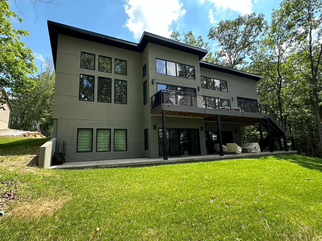 A large house with a lot of windows is sitting on top of a lush green hill.