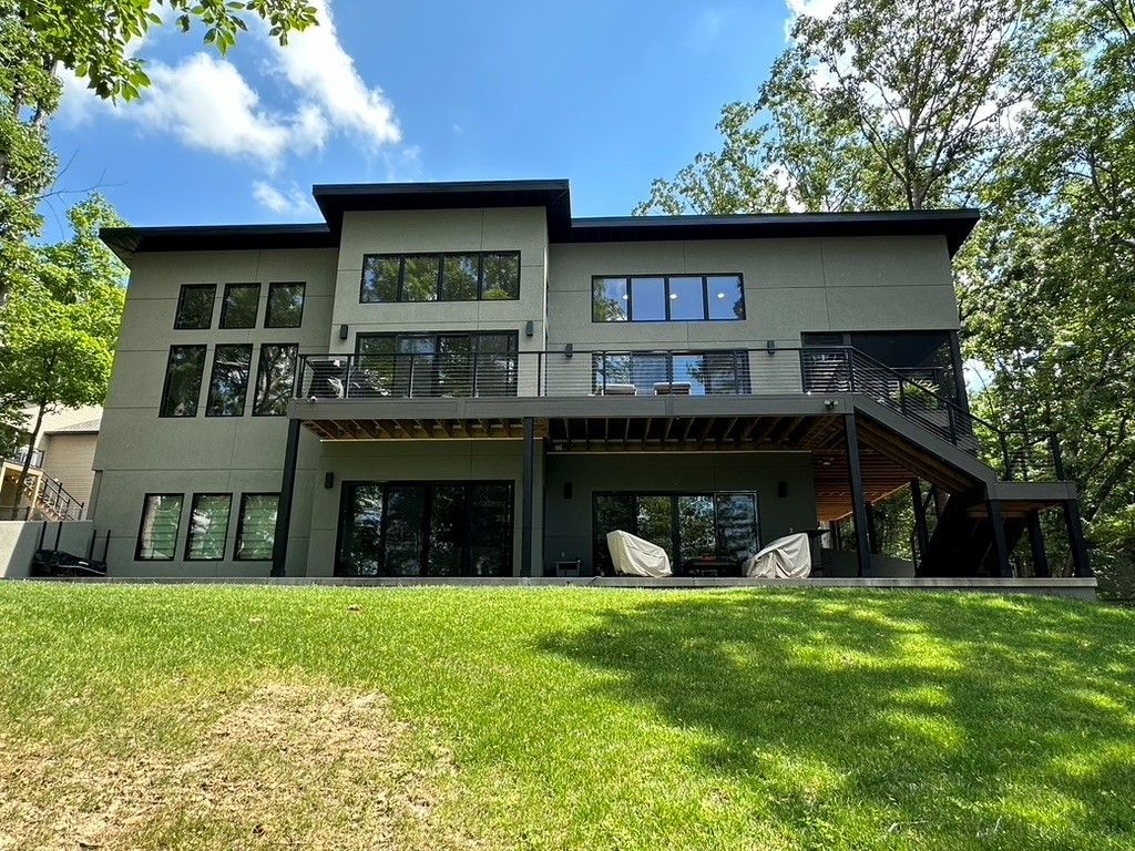 A large house is sitting on top of a lush green hill surrounded by trees.