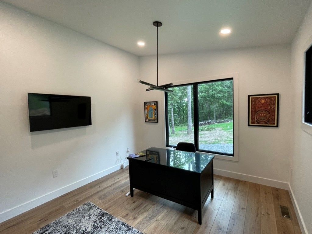 A room with a desk and a television on the wall.