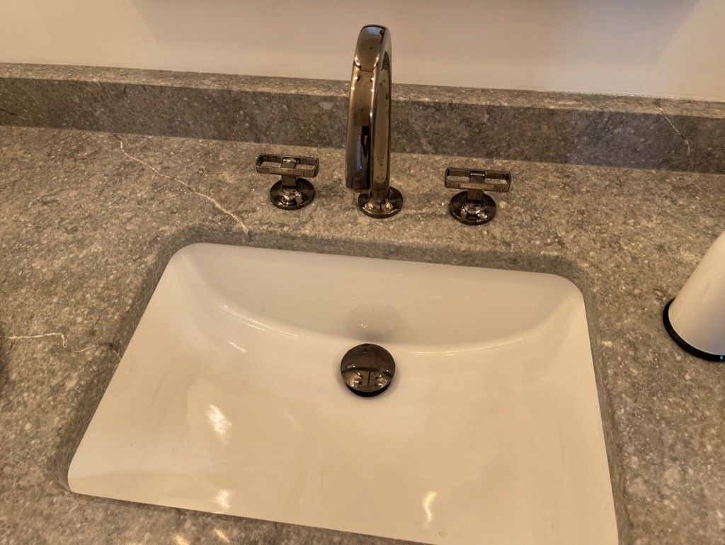 A bathroom sink with a faucet on a granite counter top.