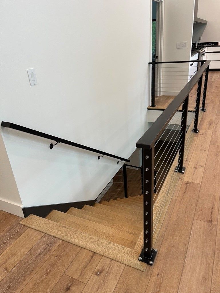 A wooden staircase with a black railing in a house.