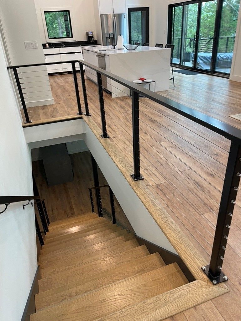 A wooden staircase with a black railing leading up to the second floor of a house.