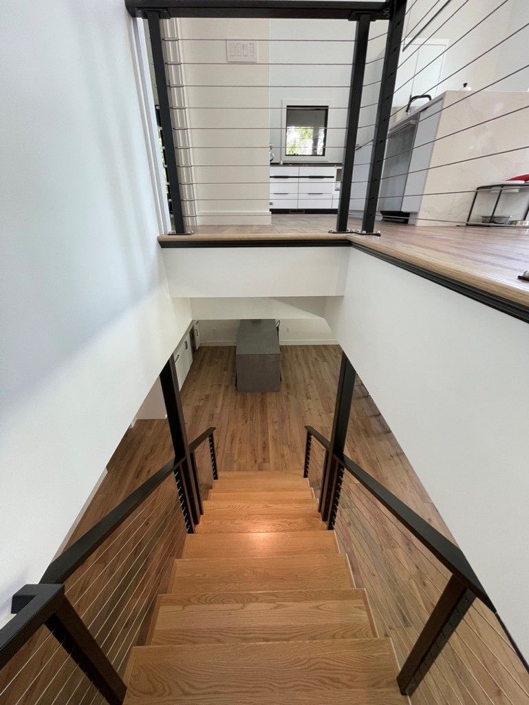 A wooden staircase with a black railing leading up to the second floor