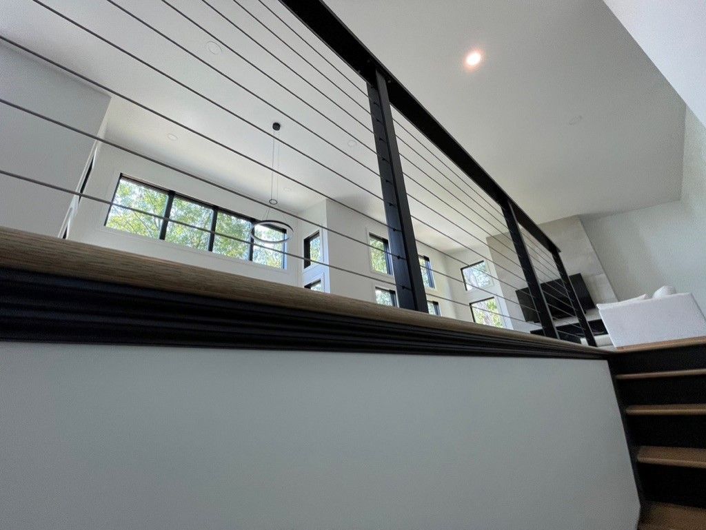 A view of a living room from a staircase with a wire railing.