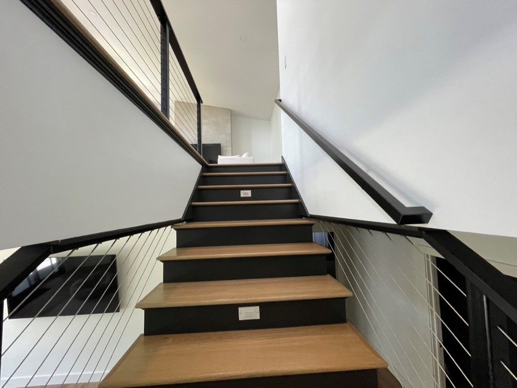 The stairs are made of wood and metal and have a wire railing