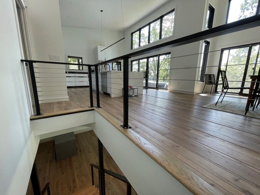 A staircase in a house with a wooden floor and a black railing.