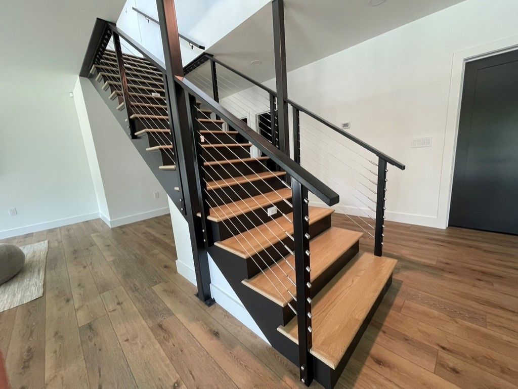 A staircase with wooden steps and a black railing in a living room.