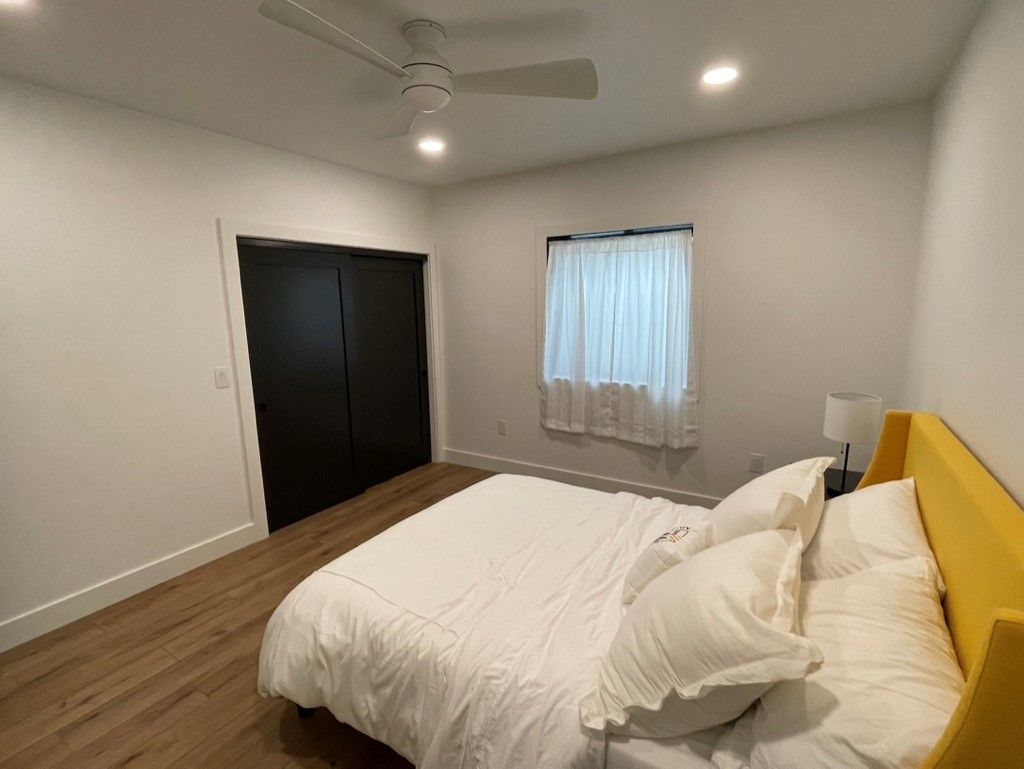 A bedroom with a large bed and a ceiling fan.