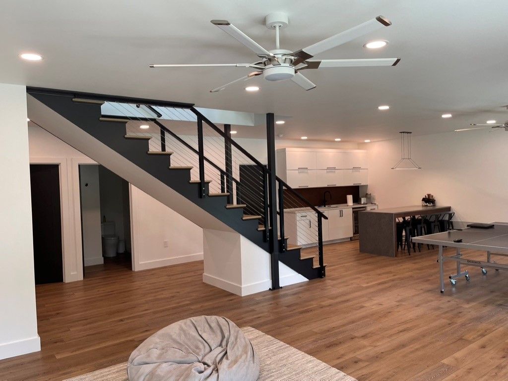 A living room with a staircase and a ceiling fan.