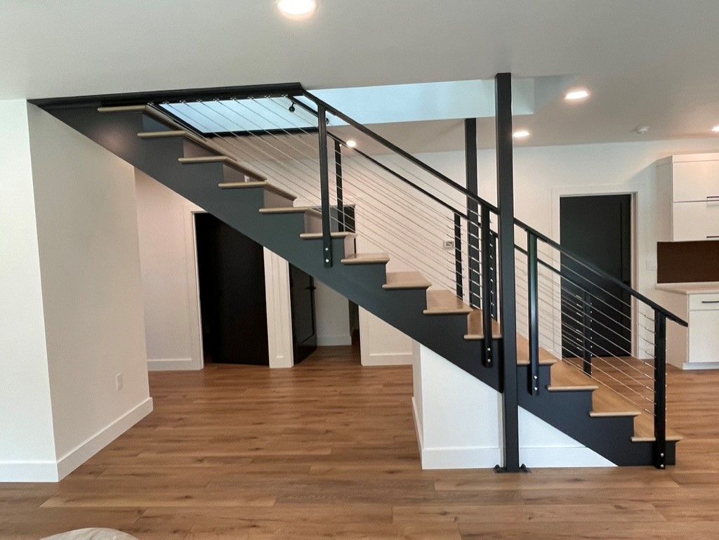 A staircase in an empty room with a black railing