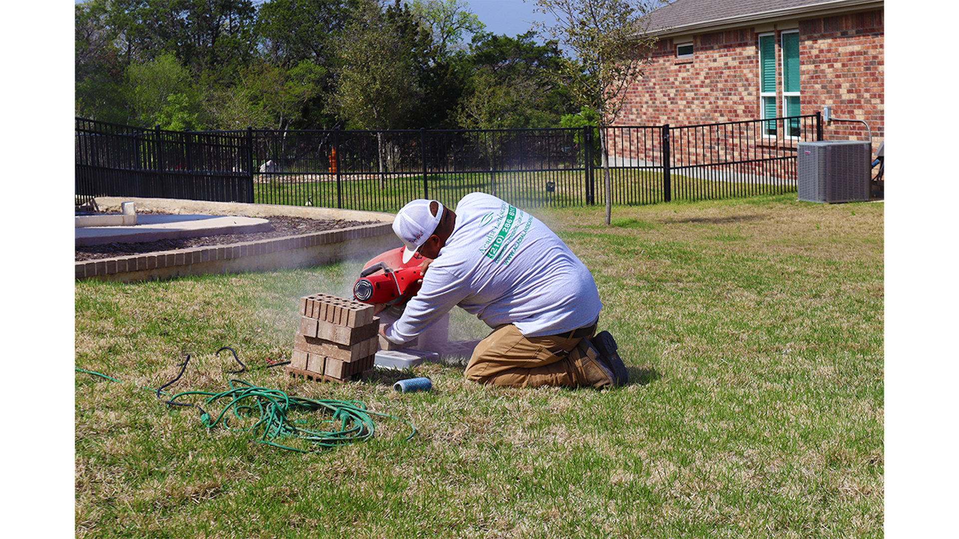 A person cutting bricks with a power saw in a yard.