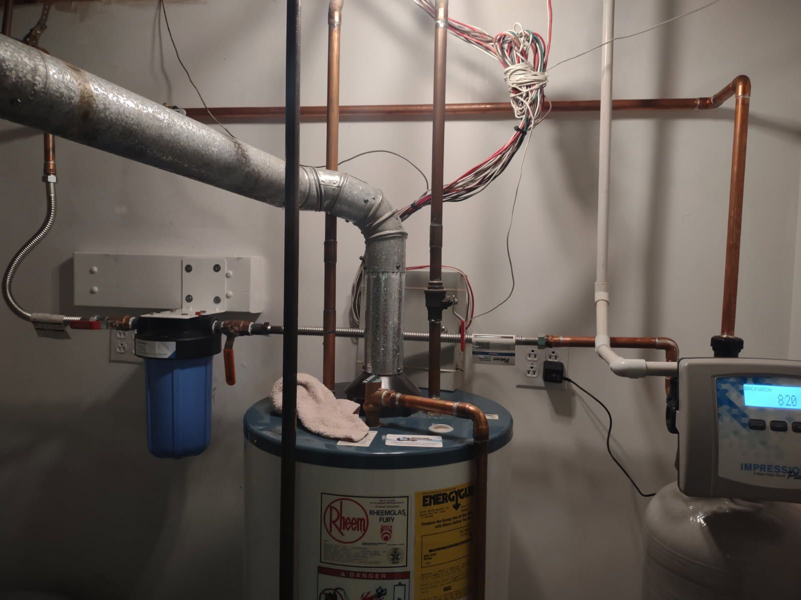 Basement utility area with water heater, pipes, and an electric meter display on the right