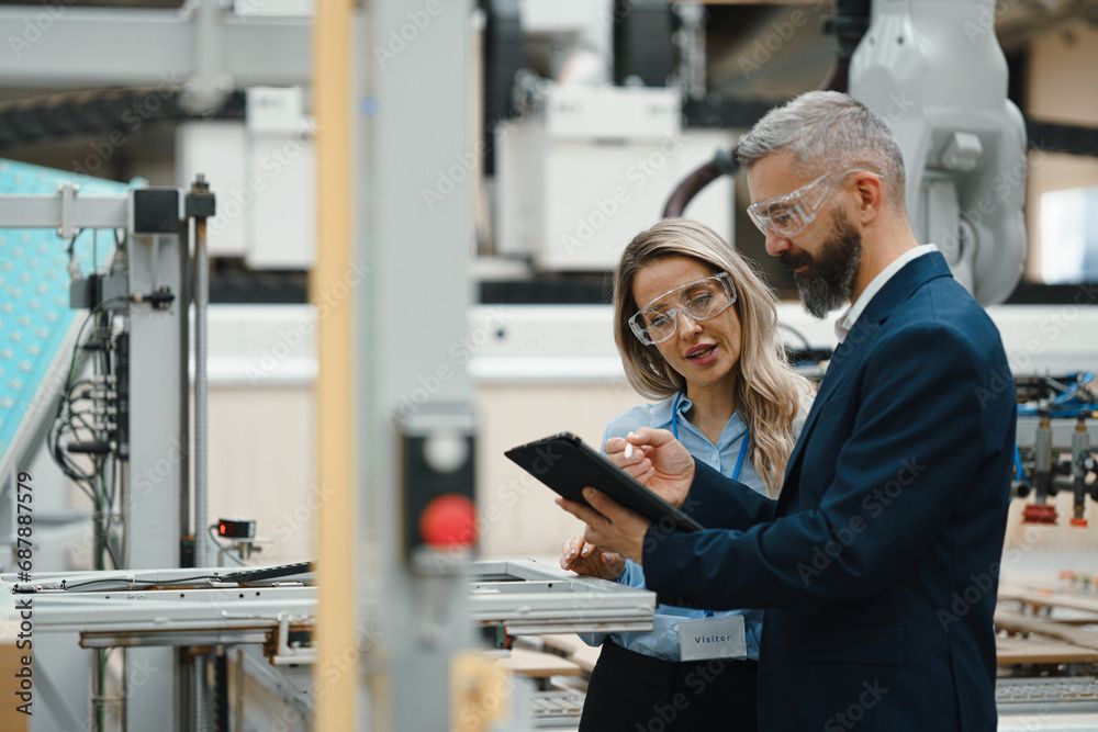 Two engineers reviewing data on a tablet in a factory workshop