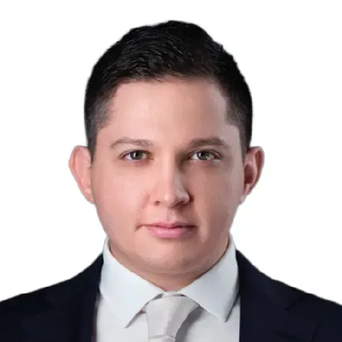 Headshot of a man in a dark suit, white shirt, and light tie on a white background
