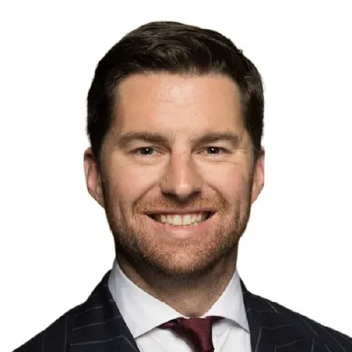 Smiling man in a dark suit and burgundy tie against a white background