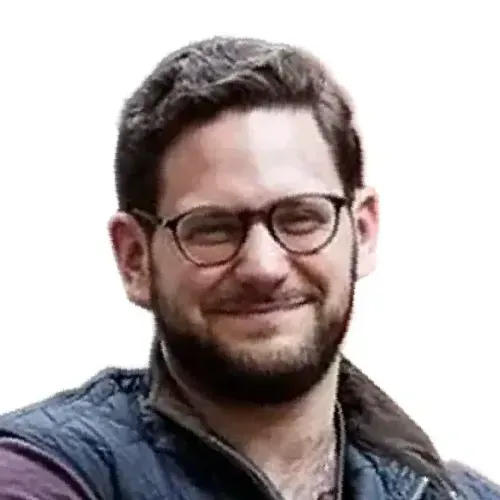 Smiling man with glasses and short dark hair, wearing a dark jacket against a white background