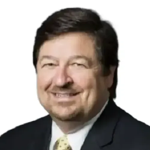Smiling man in a dark suit and tie against a white background