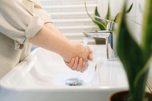 Person washing hands at a bathroom sink under running water
