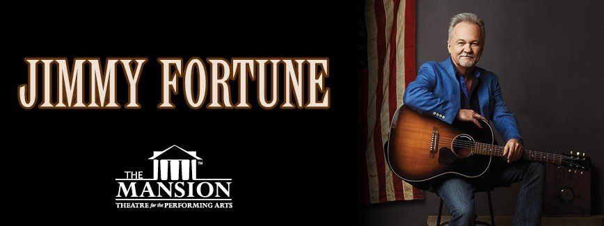 Jimmy Fortune with a guitar, seated. Performing at The Mansion Theatre, red, white, and blue backdrop.