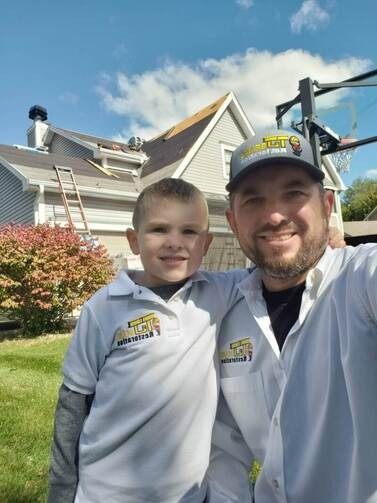 A man and a boy are posing for a picture in front of a house.