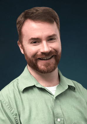 Smiling man in a light green shirt against a dark studio background