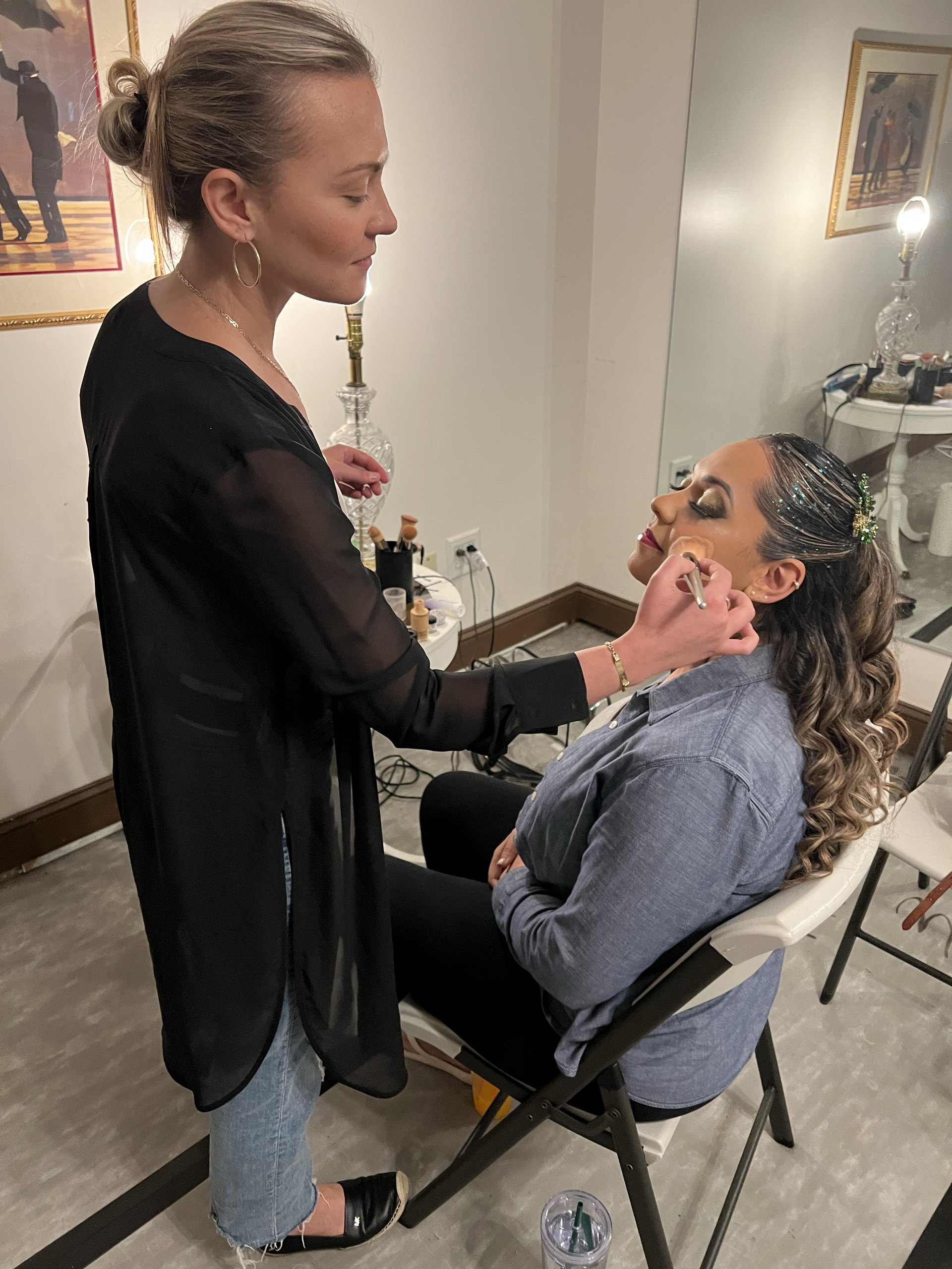 Makeup artist applying makeup to a seated client in a salon chair