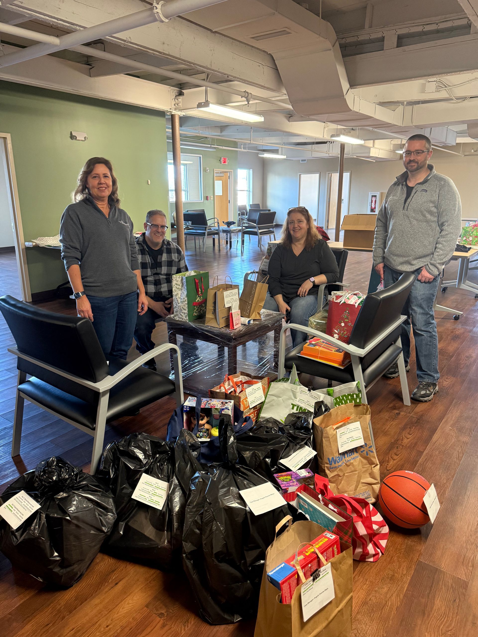 Three people in an office next to a large pile of donated bags and boxes on the floor.