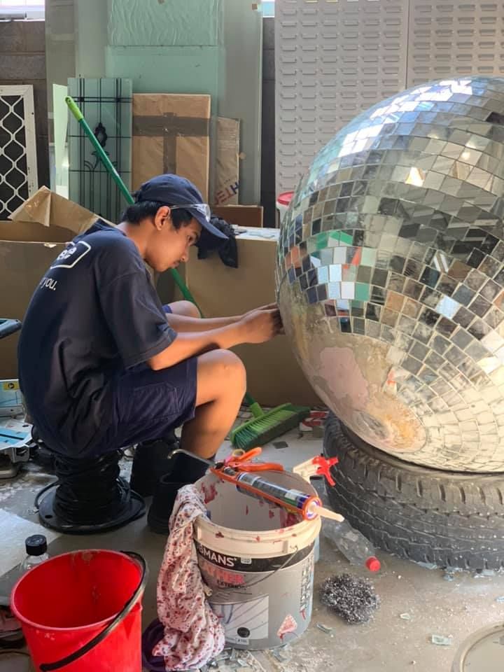Person Attaching Tiles to a Large Mirror Ball — Innisfail Glass & Aluminium in Innisfail, QLD