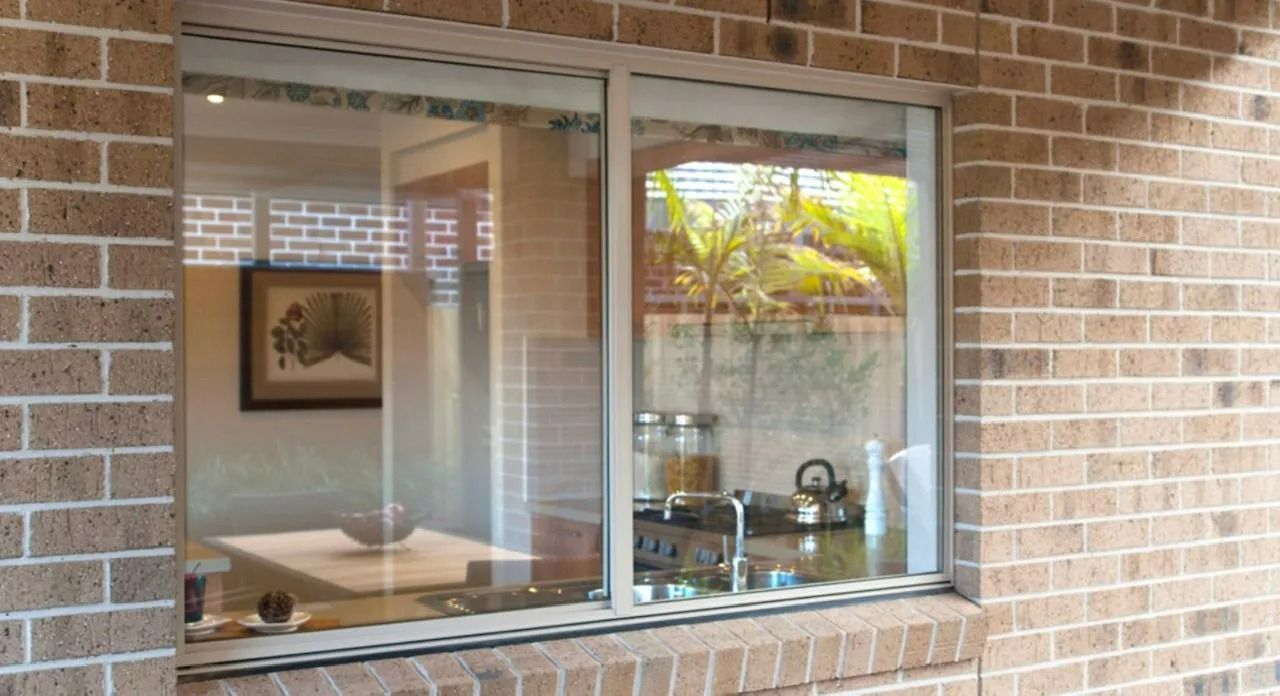 Window in a Brick Wall Reflecting an Interior — Innisfail Glass & Aluminium in Innisfail, QLD