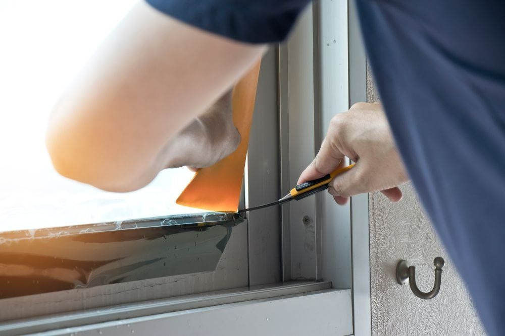 Person Applying Tint to a Window With a Yellow Tool — Innisfail Glass & Aluminium in Mission Beach, QLD
