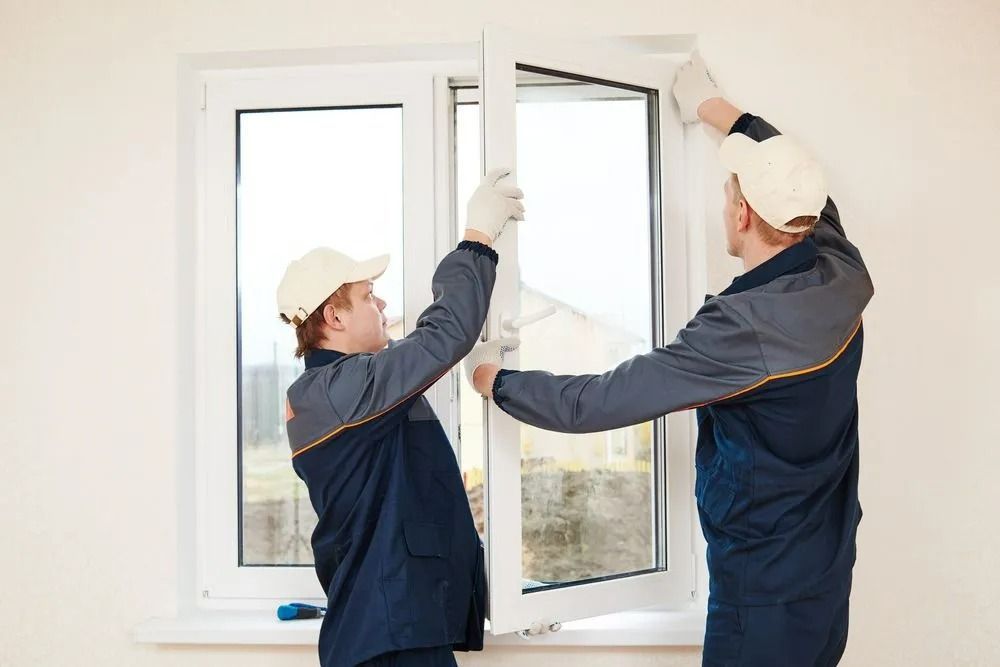 Two Workers in Blue Uniforms Install a White Window — Innisfail Glass & Aluminium in Tully, QLD