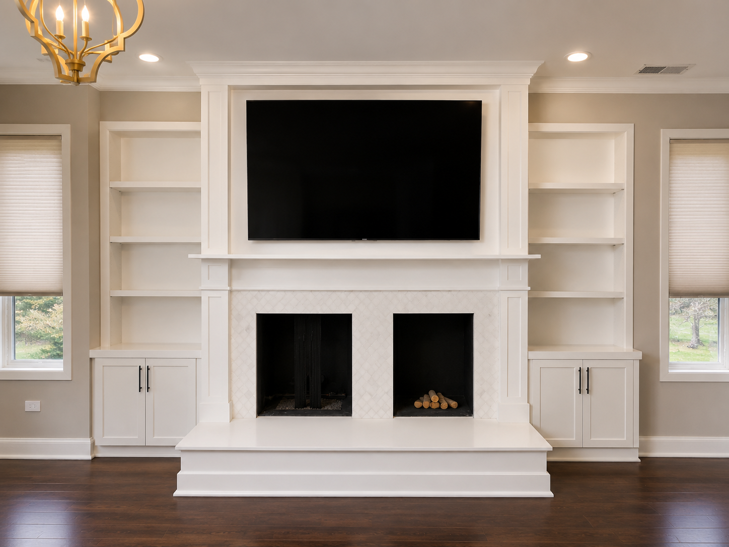 Bright living room wall with built-in shelves, a large TV, and a white fireplace over dark hardwood floors