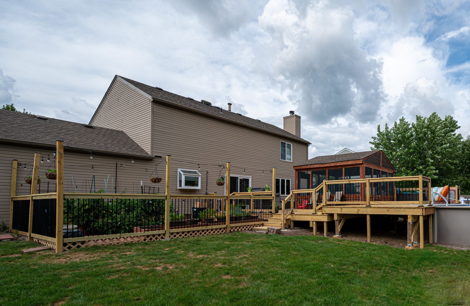 Rural house with wooden deck and ramp under construction, set on a grassy yard under a cloudy sky