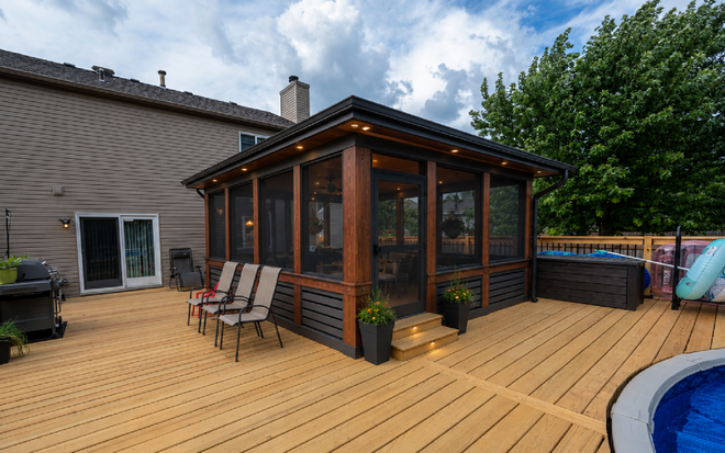 Backyard deck with sunroom, patio chairs, potted plants, and a round pool under cloudy skies