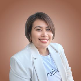 Smiling person in a white blazer and shirt against a soft pink background