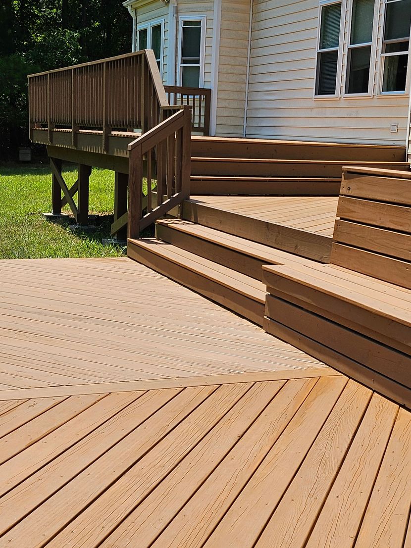 Wooden ramp and deck beside a house with tan siding and windows, in bright sunlight