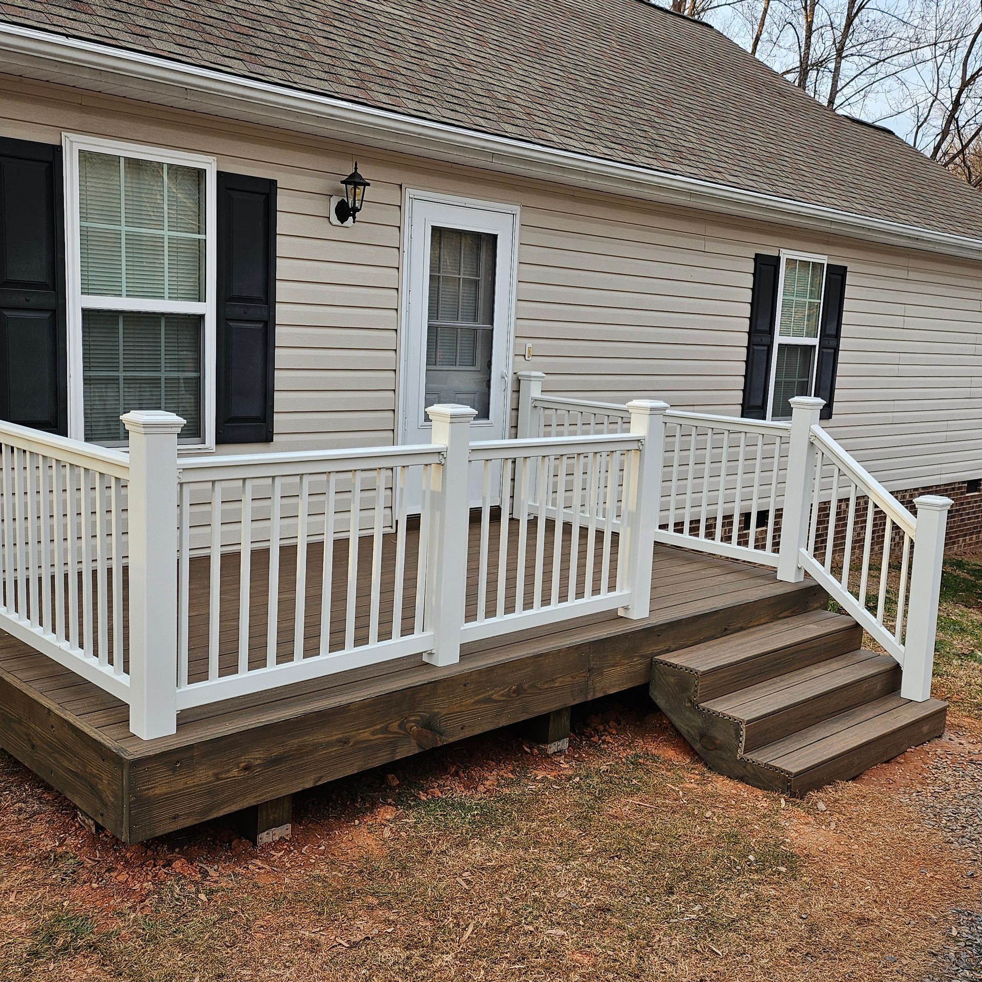 White-railed front porch with wheelchair ramp and steps on a tan house