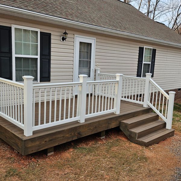 Front porch with white railings and steps on a beige house with black shutters