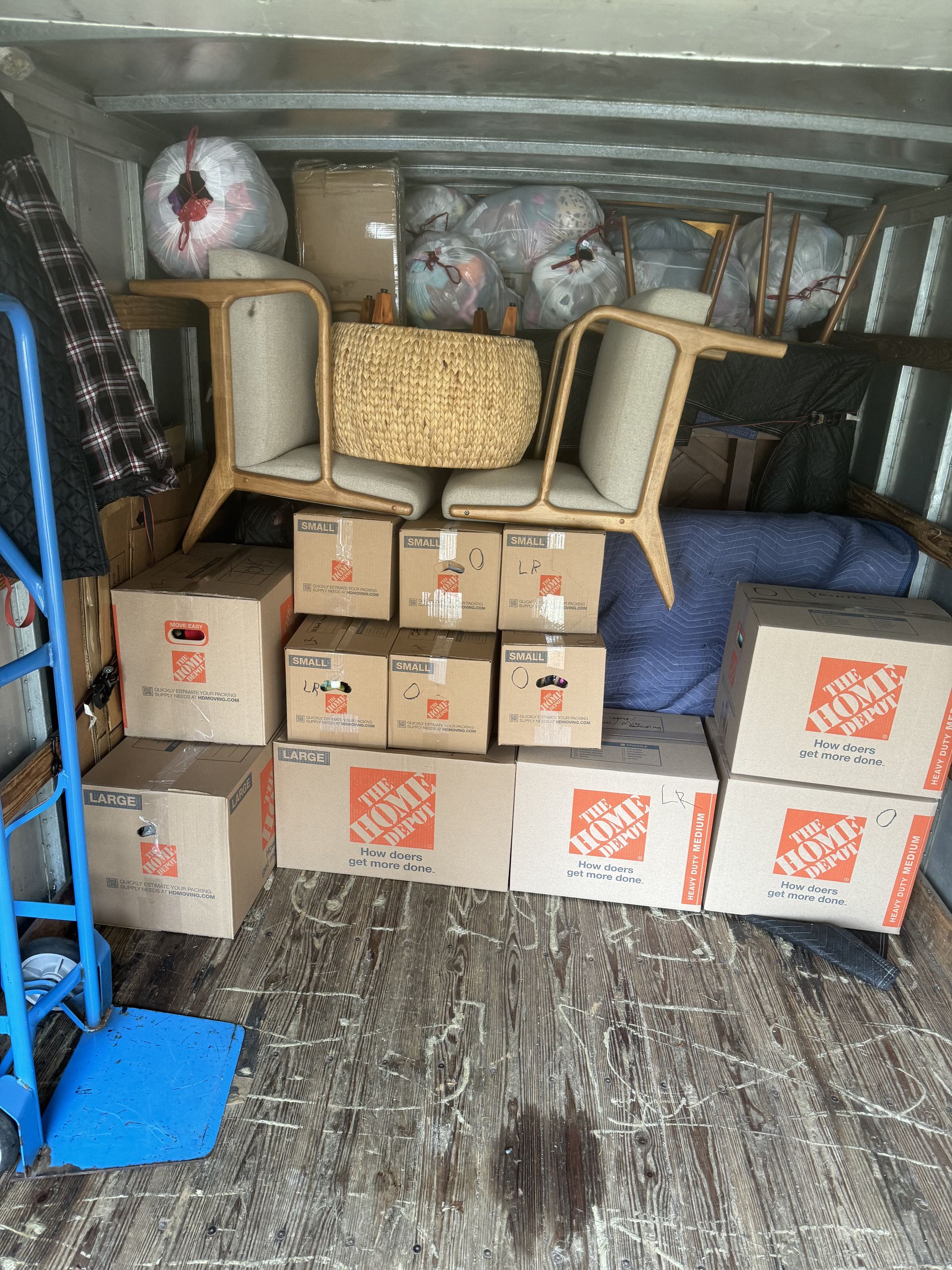 Moving van interior with furniture, boxes, and a dolly.