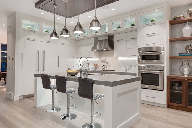 Modern kitchen with a white island, three bar stools, stainless steel appliances, and wood shelving.