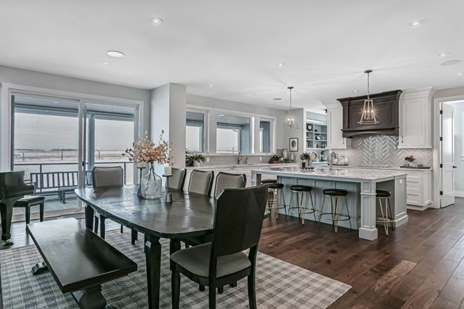 A modern, open-concept kitchen and dining area with a wood table, chairs, bench, and a large island with bar stools.