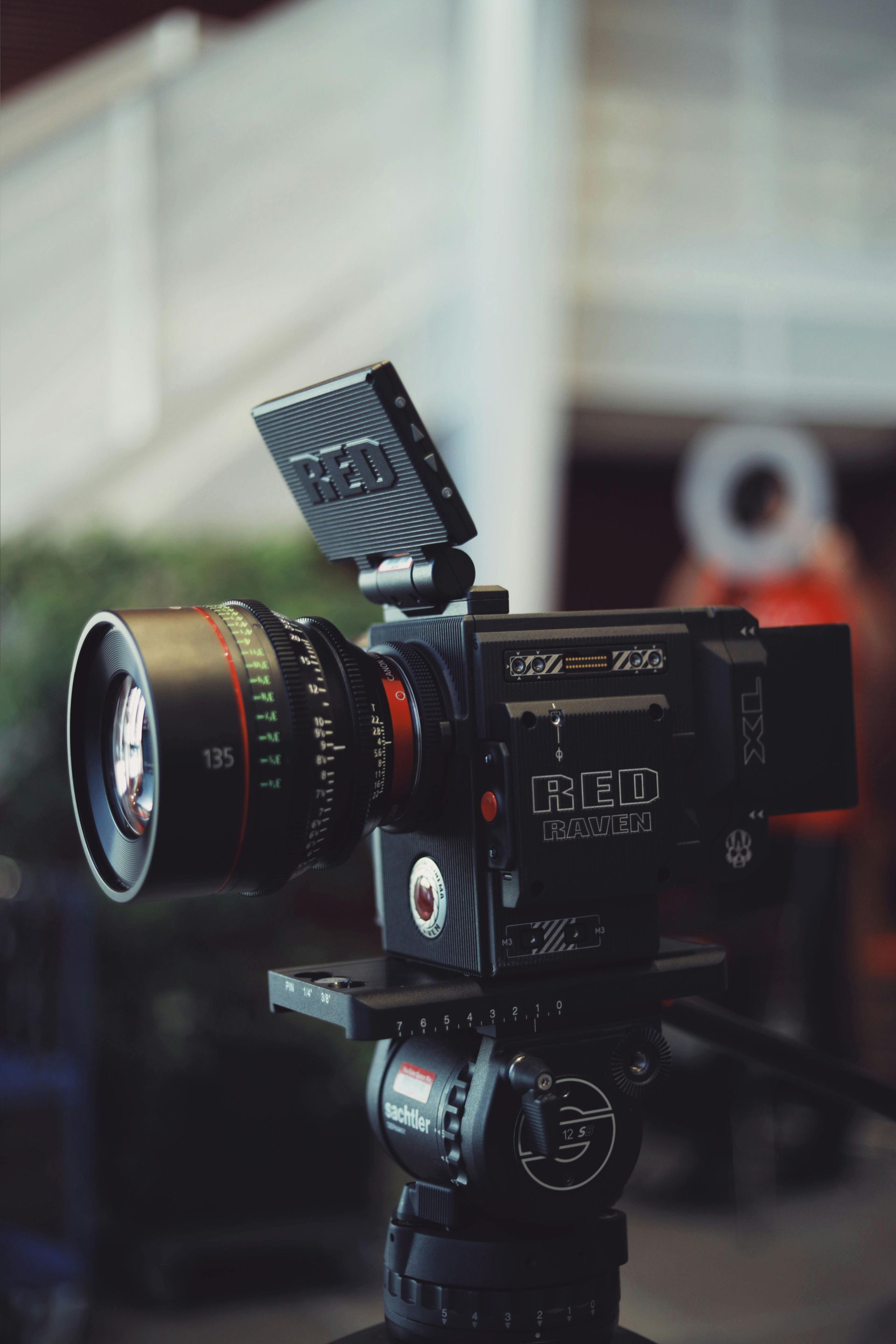 Professional video camera on a tripod, black with a large lens.