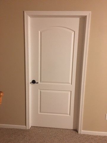A white door is sitting in a room next to a staircase.